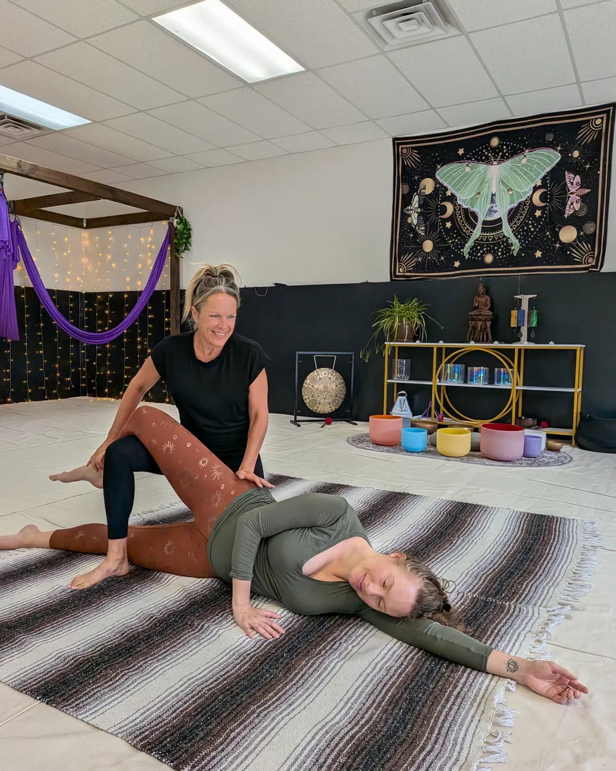Dawn guiding a Thai yoga stretch session on the sanctuary floor