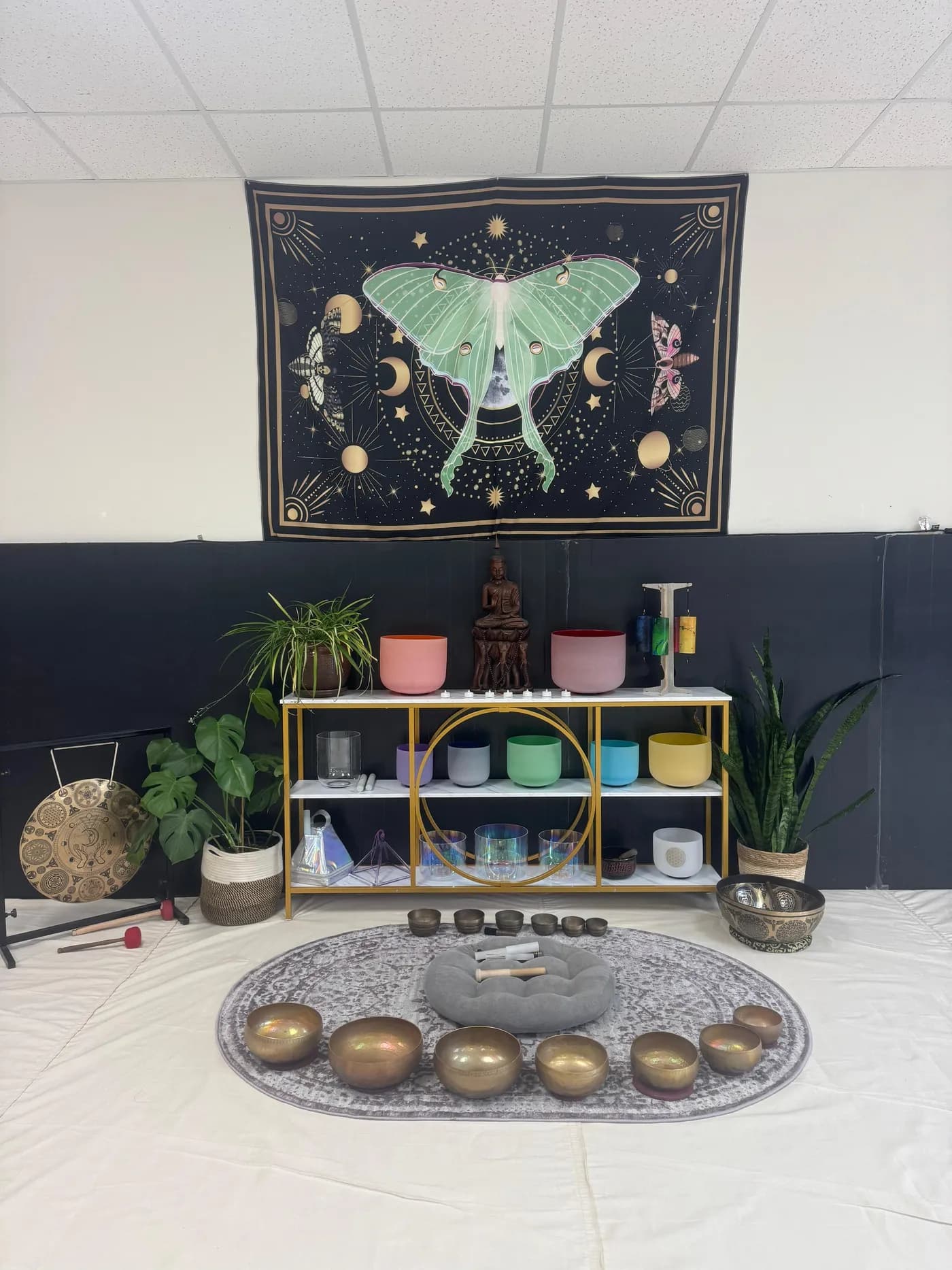 Crystal singing bowls beneath the luna moth tapestry